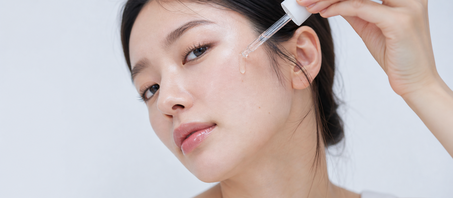 Woman applying a clear NOVELLE serum with a glass dropper