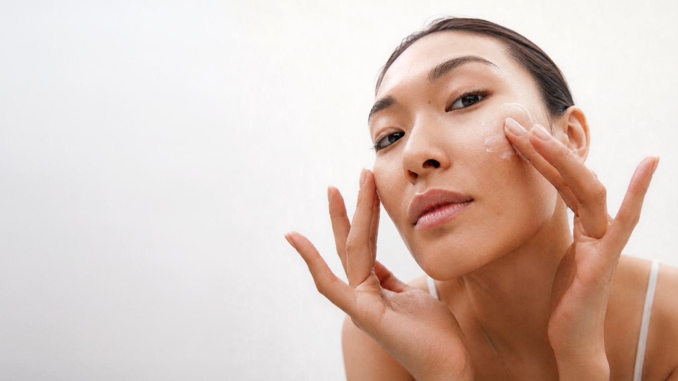 Woman applying skincare cream to her cheek
